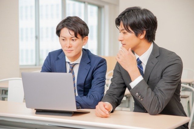 画像：パソコンをのぞき込む2人の男性のビジネスパーソン