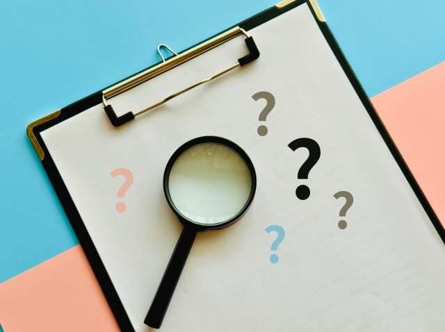 画像：はてなマークがついている書類の上に虫眼鏡が置いてある写真