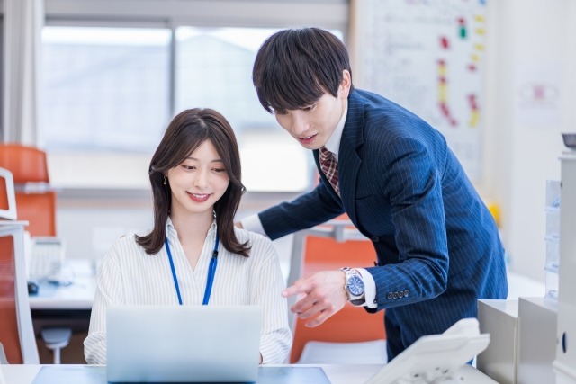 画像:パソコンの前に座る女性と、そのパソコンの画面を指さしながらのぞき込む男性の写真