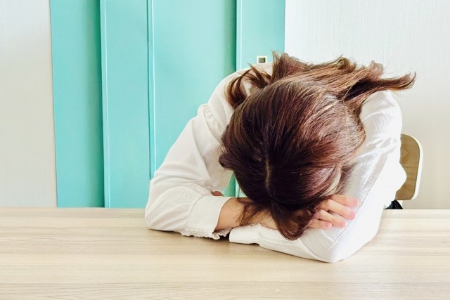 画像：机に突っ伏す女性の写真